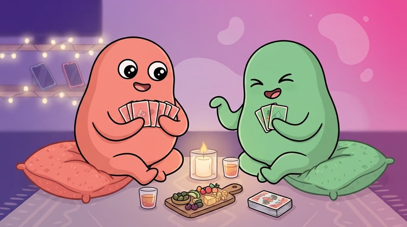 The coral and mint peek couple on a living room floor picnic by candlelight, playing a card game and laughing, phones face down out of reach.